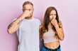 © Krakenimages.com - Young couple of girlfriend and boyfriend hugging and standing together smelling something stinky and disgusting, intolerable smell, holding breath with fingers on nose. bad smell