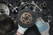 Old car clutch disk in car service worker hands close up on black table background.