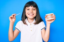 Young Little Girl With Bang Holding Invisible Aligner Orthodontic And Braces Smiling With A Happy And Cool Smile On Face. Showing Teeth.