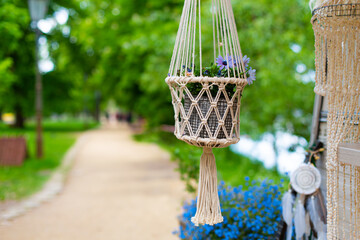 Wall Mural - Decorative flowerpot suspended from a rope in a city park. Cozy Europe