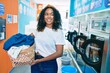 Young african american woman with curly hair smiling happy doing chores at the laundry
