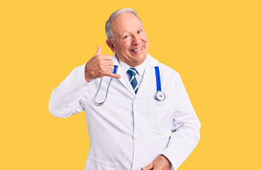 Senior handsome grey-haired man wearing doctor coat and stethoscope smiling doing phone gesture with hand and fingers like talking on the telephone. communicating concepts.