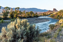 Rock Outcropping Over The River With Trees And Shrub On The Banks And Mountain In The Background, South Fork Shoshone River, Cody, Wyoming