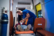 © Anna Kosolapova - Unconscious woman lying on a stretcher in an ambulance car, a paramedic providing her first aid.