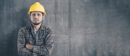 Wall Mural - Portrait Asian construction worker on cement wall background with copy space