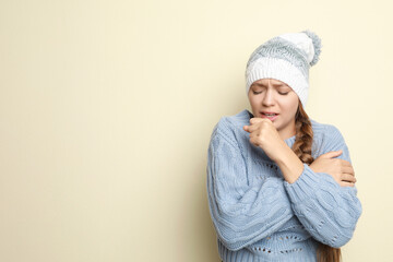 Wall Mural - Young woman wearing hat coughing on light background, space for text. Cold symptoms