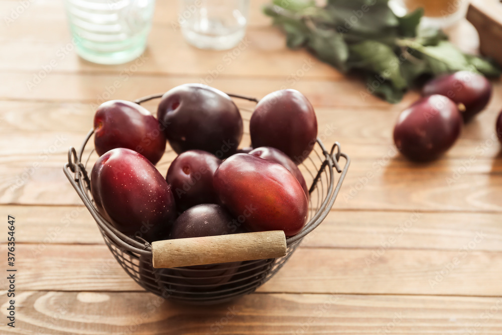 Basket with tasty sweet plums on table