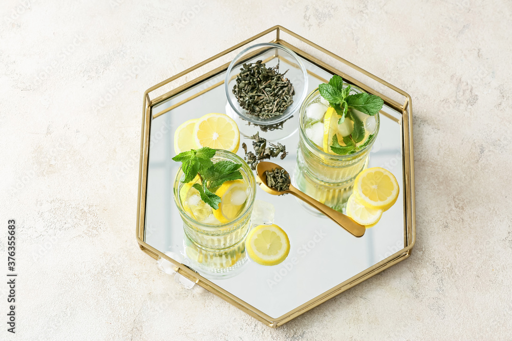Tray with glasses of tasty cold ice tea on light background