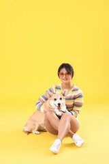 Wall Mural - Woman with cute corgi dog on color background