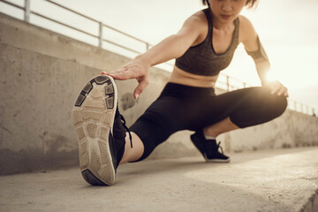 Focus sport shoe, Runner doing stretching exercises on stair before running at sunset. Asian woman warm up stretching exercise in park outdoor.