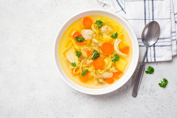 Wall Mural - Homemade chicken soup with noodles and vegetables in white bowl, white background, top view.