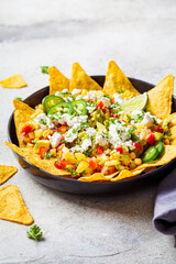 Poster - Mexican street corn salad with cheese and nachos chips in black plate. Mexican food concept.