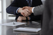 © Iryna - Handshake as successful negotiation ending, close-up. Unknown business people shaking hands after contract signing in modern office