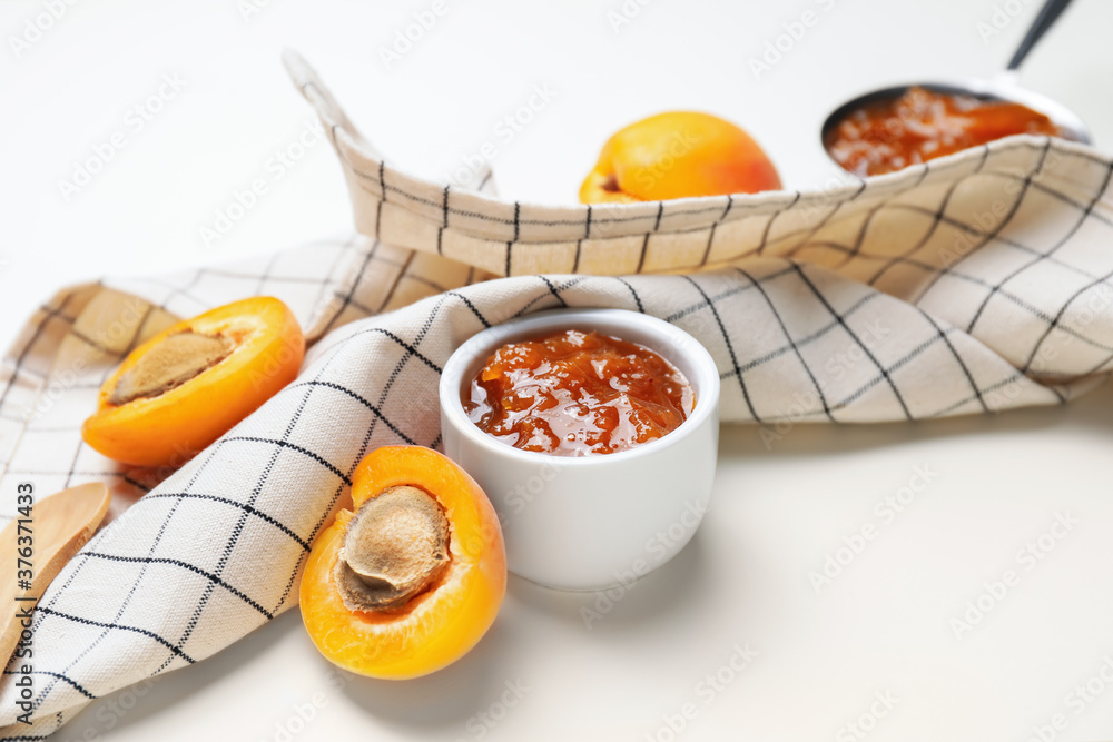 Bowl of tasty apricot jam on white background