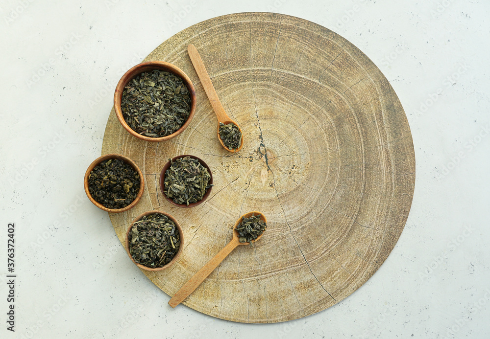 Bowls and spoons with dry tea leaves on table