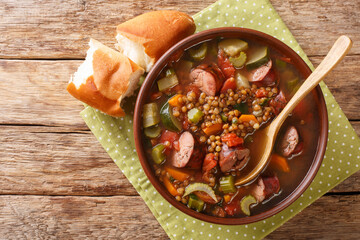 Delicious hot sausage lentil soup with seasonal vegetables close-up in a plate on the table. horizontal top view from above