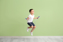 Cute Little Boy Jumping Rope Near Color Wall