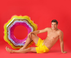 Wall Mural - Young man with inflatable ring on color background