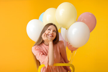 Sticker - Young woman with balloons sitting on chair against color background