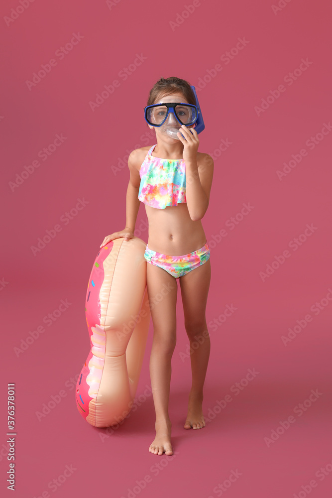 Little girl with swimming ring on color background
