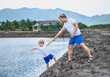 © NOVOZHILOV ANDREI - Dad helps son go down to lake water, explains safety rules. Family together walk play. Home natural child education, fathers day, fatherly responsibilities, influence on formation of son worldview