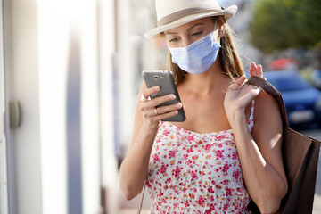 Wall Mural - Young woman doing shopping in tourist area, wearing face mask