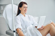 © Viacheslav Yakobchuk - Smiling spa client using a gadget during a medical procedure