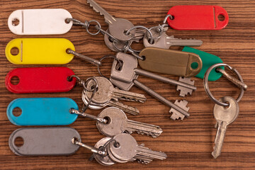 Close up of keys with colorful key rings on natural wood background