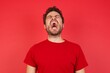 © Roquillo - Young handsome caucasian man wearing t-shirt over isolated red background angry and mad screaming frustrated and furious, shouting with anger. Rage and aggressive concept.