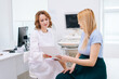 © dikushin - Female doctor transmits results of ultrasound examination to pregnant young woman. Obstetrician gynecologist talking with pregnant girl in white room at medic clinic. Concept of happy childbearing.