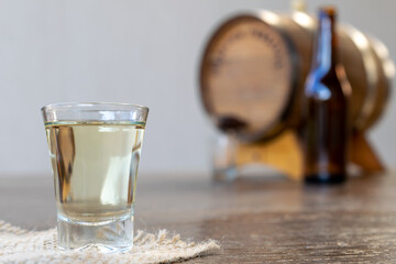 detail of white cachaça glass and vat and bottle on blurred background.