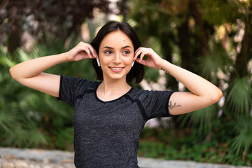 Young sport caucasian woman listening music at outdoors in a park