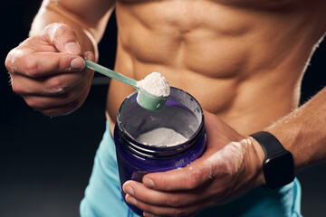 Wall Mural - Athletic man holding a container with protein powder