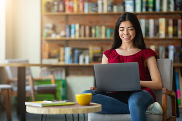 Smiling korean girl using laptop for online work or studies at cafe