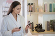 © zinkevych - Woman in white robe choosing products for beauty care and looking involved