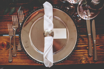 Wedding banquet, serving wooden table with silver plates and decorated with flowers