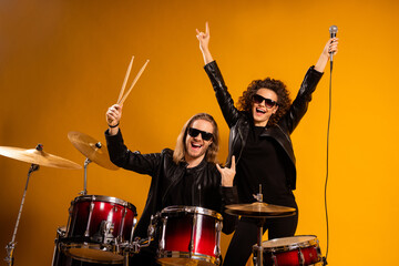 Wall Mural - Photo of rock group band cool guy play instruments beat drum sticks crazy attractive redhair girl sing mic popular song showing horns wear black leather outfit isolated yellow background