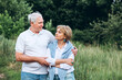 © Stanislav - mature couple is walking with dog in park. Elderly couple resting in nature with a dog. Full-length portrait of an elderly man and woman in white shirts and jeans. Stylish and modern grandparents.