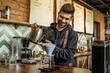 © Тарас Нагирняк - Portrait of barista male brews a single cup a coffee house employee brew a single cup of coffee using a unique system. The hot water drips through the filter, focus on brewing system