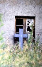 Cross Of A Tombstone Leans At A Broken Window