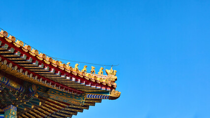 traditional Chinese roofs with figurines on the blue sky background. The Imperial Palace in Beijing