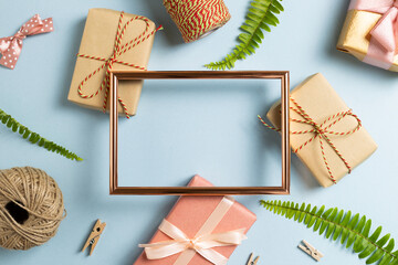 Gift wrapping concept. Empty photo frame with gift boxes on sky blue background. top view, copy space