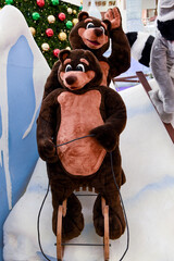 Two brown bears on a sleigh are rolling down the hill. Christmas card with two bears. Christmas composition made of toys and snow.