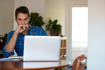 Young man deep in thought while working remotely from home