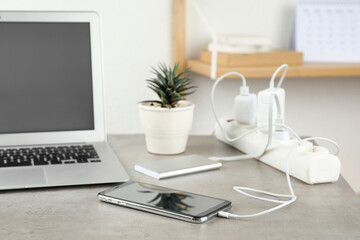 Devices charging with cable on light stone table