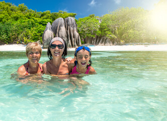 Canvas Print - Young girl with mother and grandmother relaxing in the water, Seychelles Islands