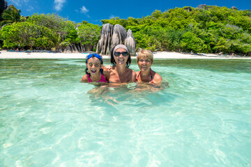 Wall Mural - Young girl with mother and grandmother relaxing in the water, Seychelles Islands