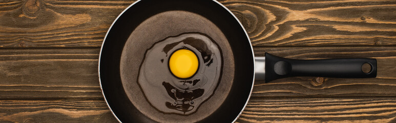 Sticker - top view of fresh smashed chicken egg in frying pan on wooden surface, panoramic shot