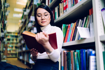 Asian female reading interesting book in library