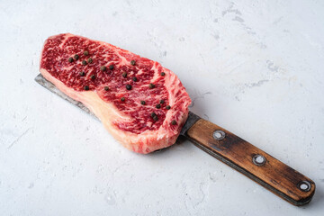 Wall Mural - Raw beef steak on a meat cleaver on a white table